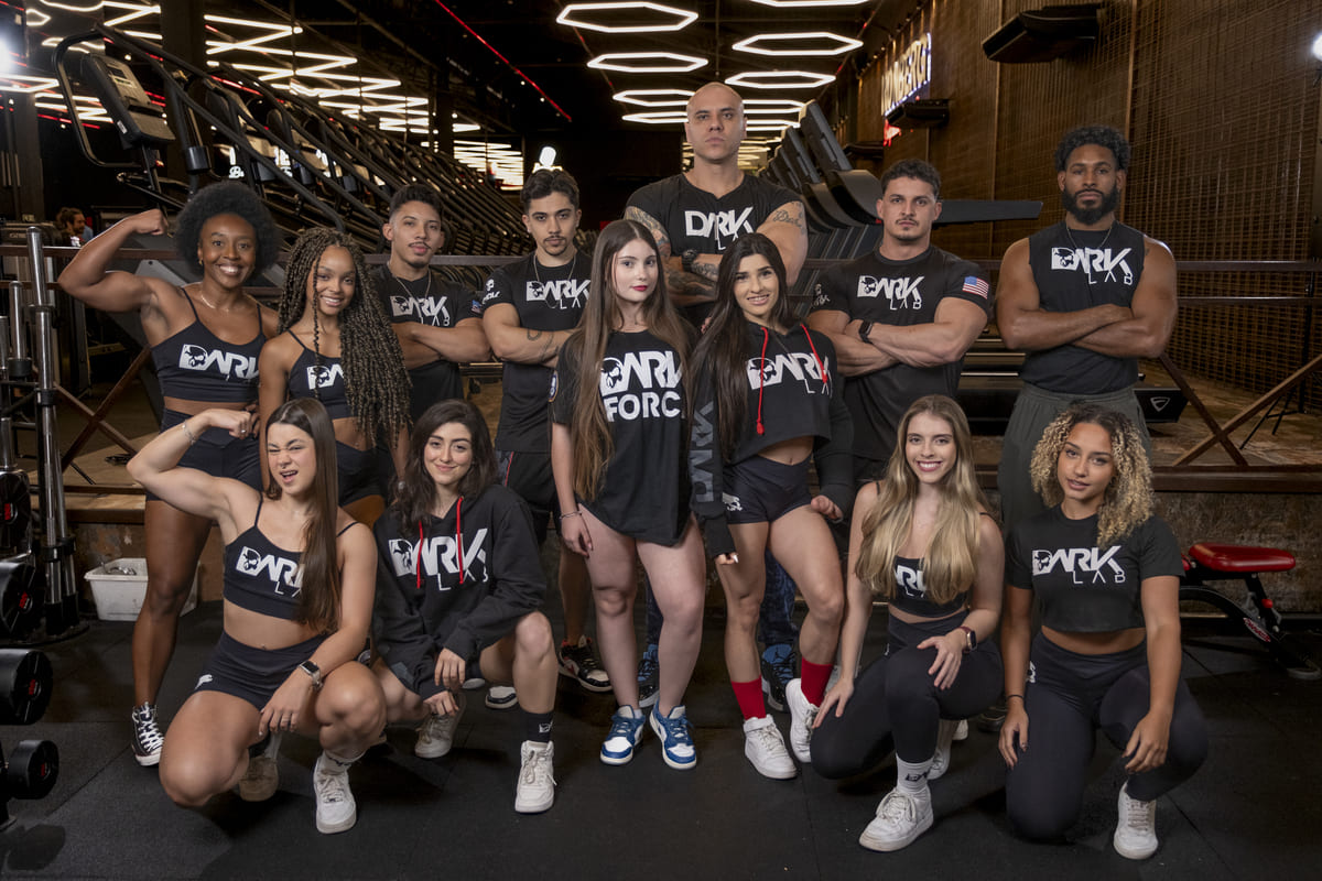 Equipe DARK LAB, composta por atletas diversos (homens e mulheres), posa em uma academia, prontos para a Black Friday 2025.