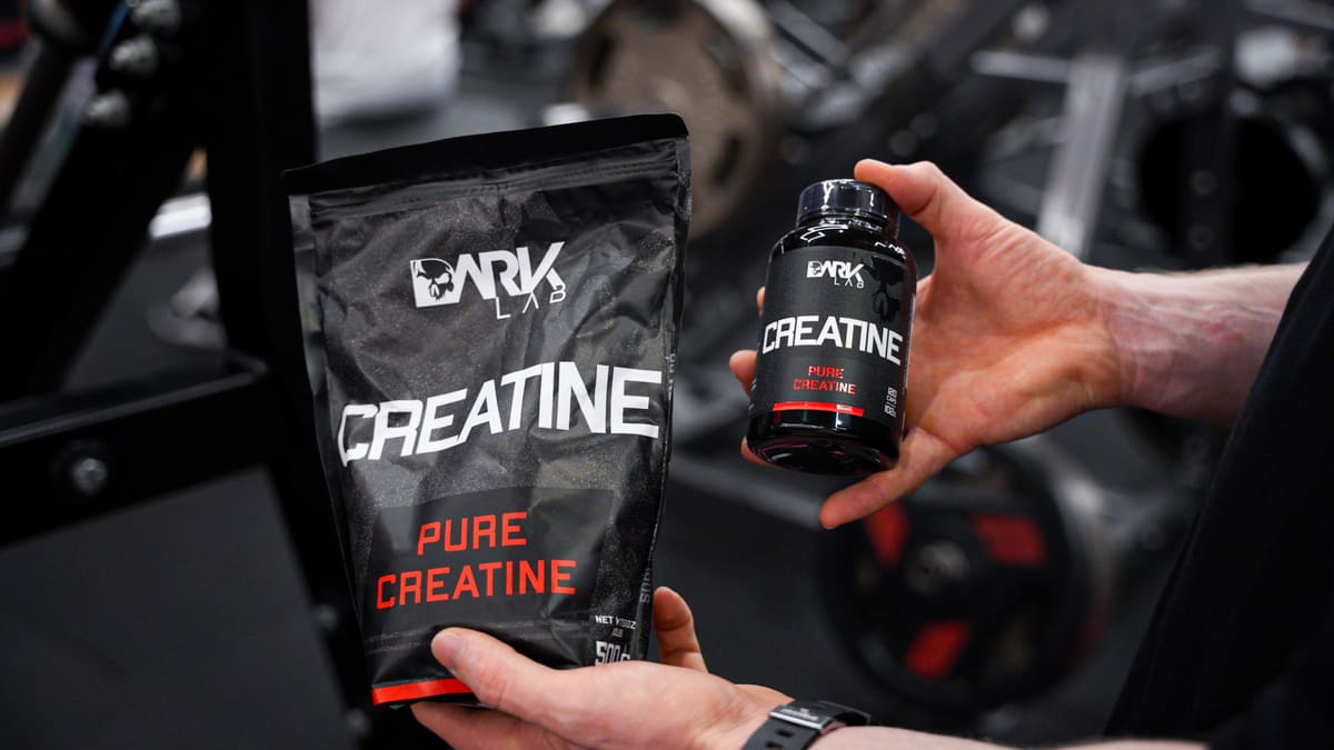 Mãos apresentam embalagens em saco e pote da Dark Lab Pure Creatine na academia, ilustrando opções de creatinas aprovadas pela anvisa.