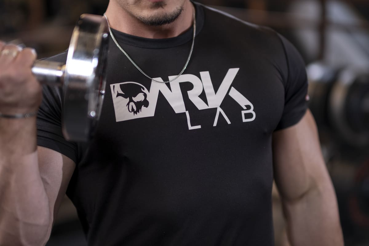 Homem musculoso em foco, usando uma camiseta da Dark Lab e levantando um halter, ilustrando a dedicação e os resultados proporcionados pelos produtos da melhor loja de suplementos online.