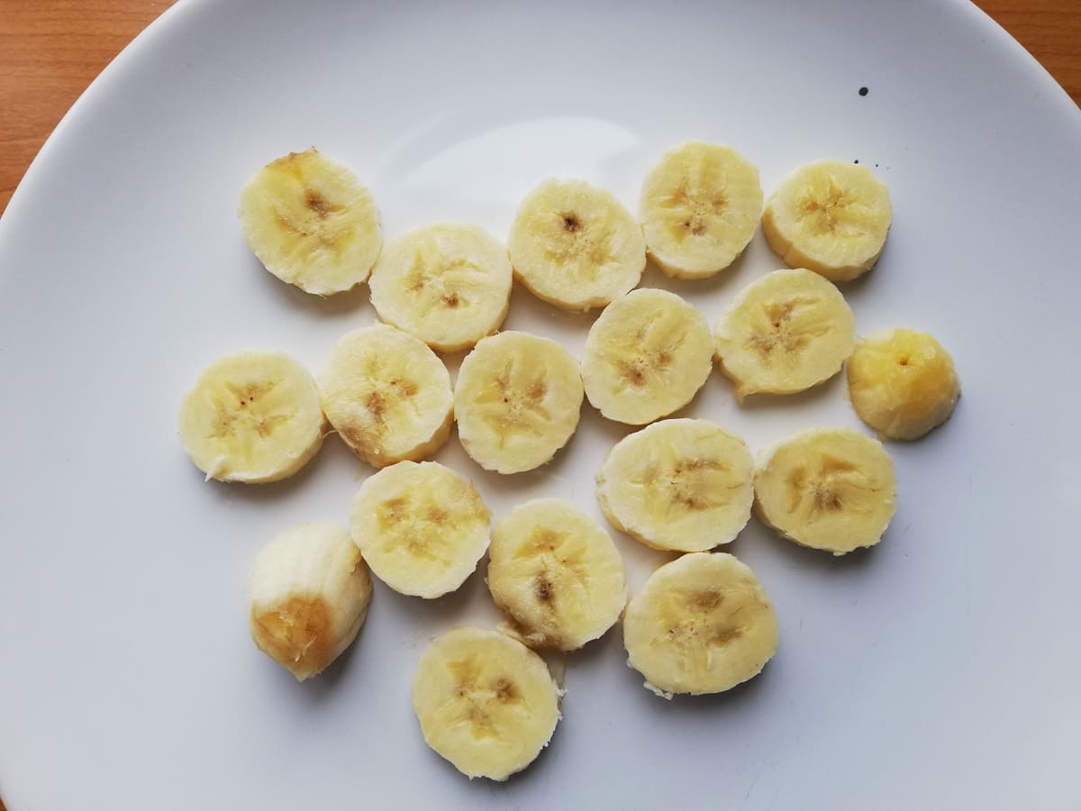 Rodelas de banana madura, um dos alimentos ricos em carboidratos naturais, dispostas sobre um prato branco.