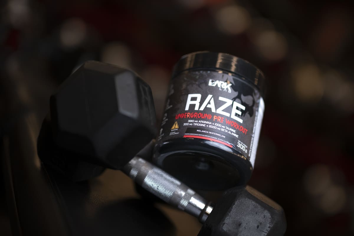 Pré-treino Raze Dark Lab ao lado de halter para treinar até a falha muscular.